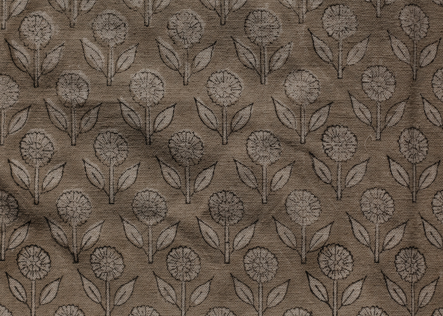 Brown block print pillow with a subtle pattern of leaves and flowers.